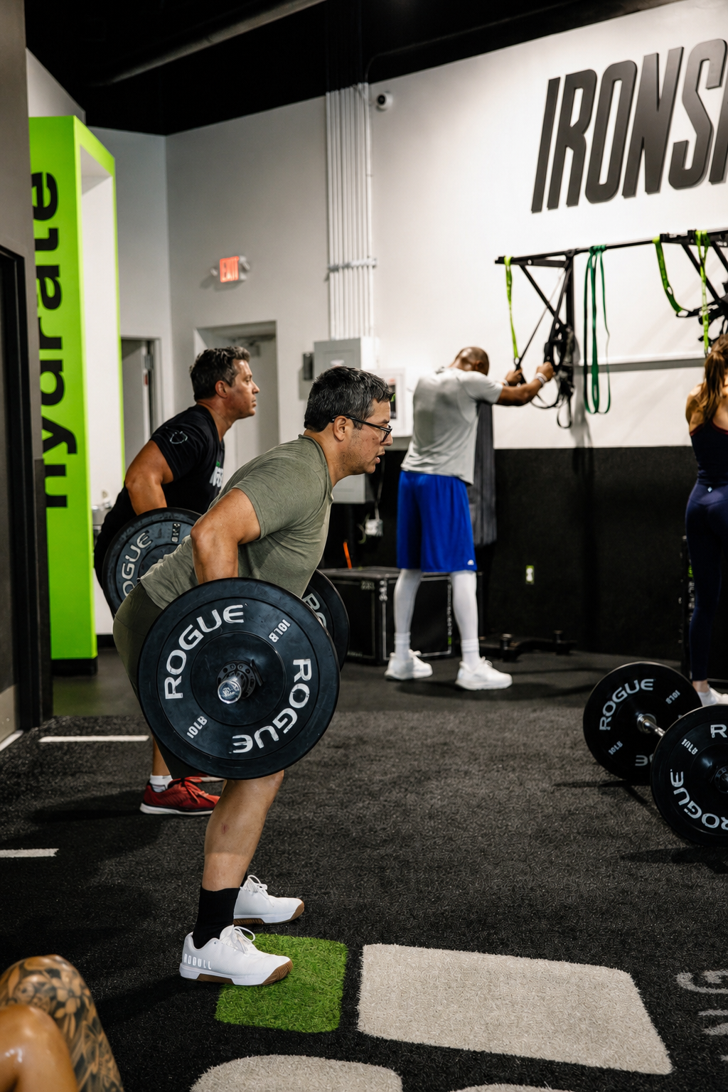 Athletes bent over rows with Rogue barbells on the ISI floor