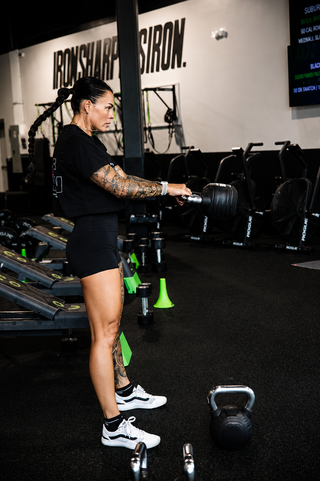 An athlete mid kettlebell swing under the IRON SHARPENS IRON wall